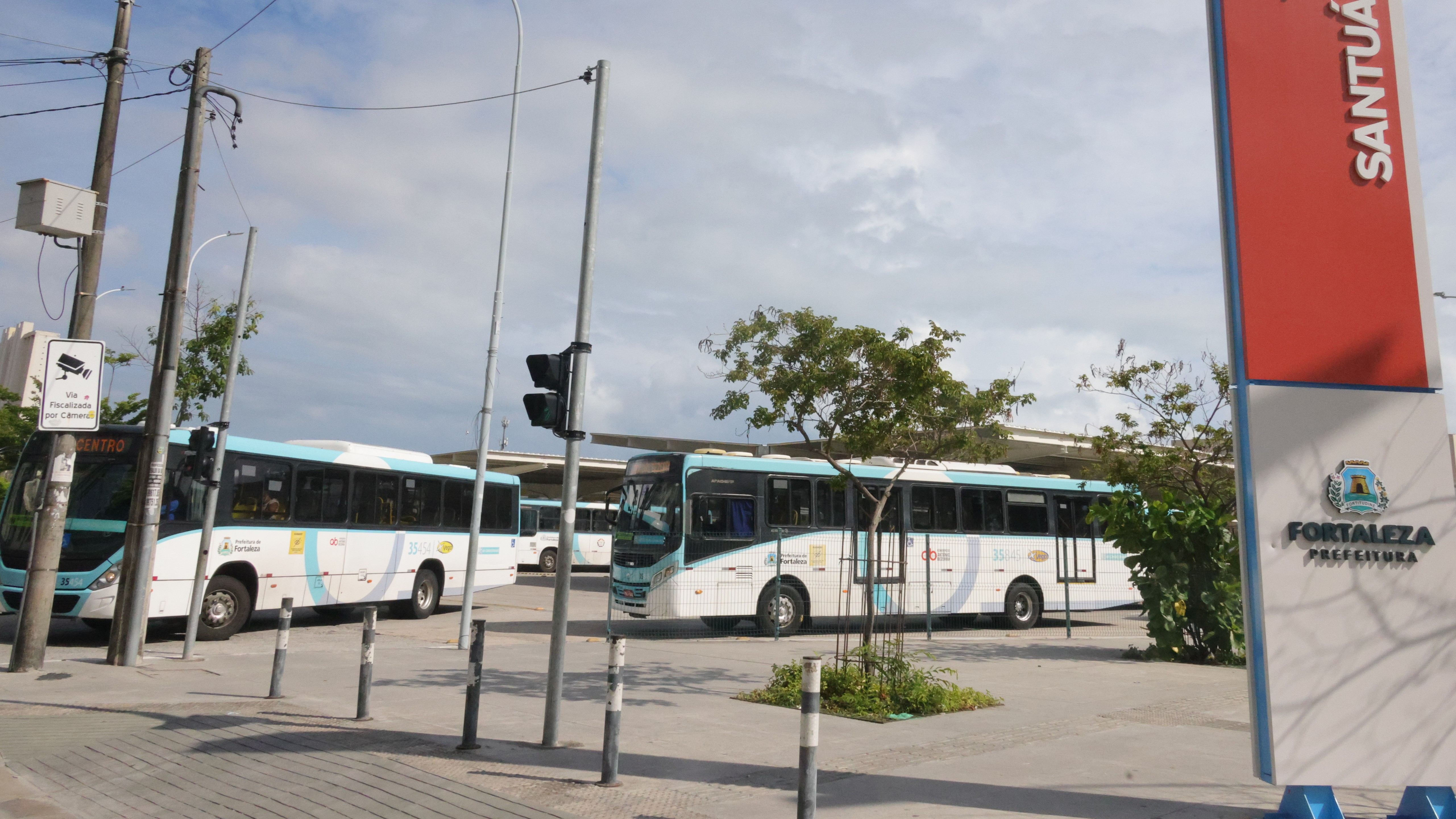 dois ônibus circulando no terminal aberto localizado na Praça José de Alencar